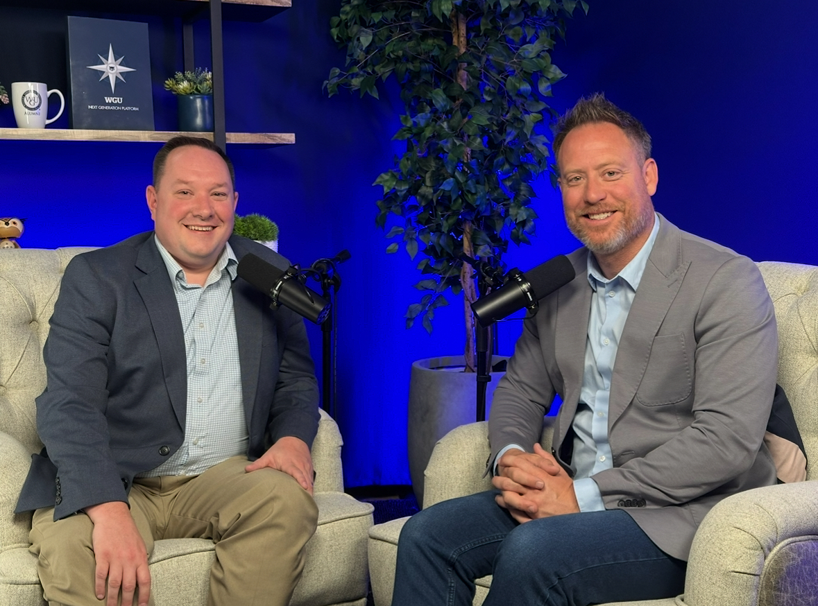 Two smiling men seated with microphones in a podcast studio.